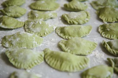 Küflenmiş çiğ hamur köfteleri ile yemek geçmişi. Varennyky ve ravioli, mutfak masasının un kaplı mermer yüzeyinde. Ukrayna geleneksel mutfağı. Yiyecekler. Gelenekler ve kültür. Yakın plan.