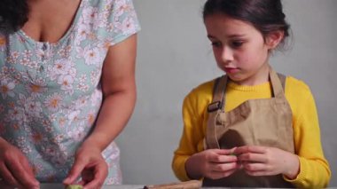 Küçük kız Ukrayna usulü Varennyky ya da İtalyan mantısı yapmayı öğreniyor. Annesinin aile yemeği için hamur işi yapmasına yardım ediyor. - İnsanlar. Mutfak. Mutfak.