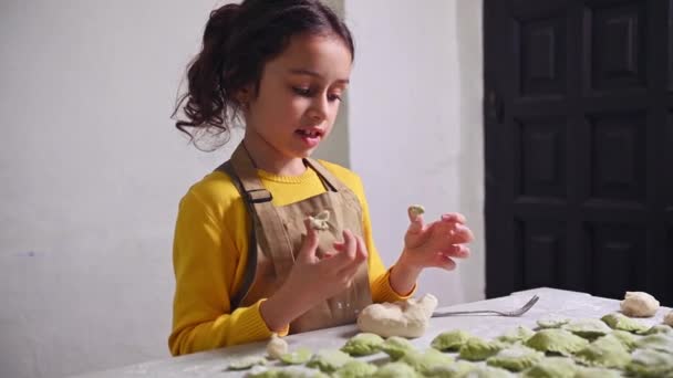 穿着米黄色围裙的小女孩在家里厨房做饺子的时候玩得很开心 — 图库视频影像