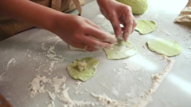Ev hanımı hamuru patates püresiyle dolduruyor, geleneksel aile tarifine göre ev yapımı varenyky, hamur tatlısı, ravioli hazırlıyor, mermer mutfak masasında malzemelerle duruyor. Üst görünüm