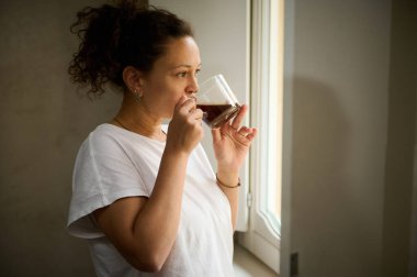 Çekici bir kadın kahve içiyor ve rüyasında pencereden bakıyor.