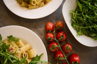 İtalyan makarna makarna, pancetta pastırması ve pekorino parmesan peynirli Amatriciana 'nın yanında taze olgun organik domates dalıyla besin arkaplanı. İtalyan mutfağı. Üst görünüm