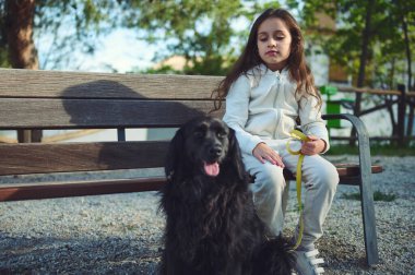 Beyaz, tapılası küçük bir kız çocuğu, şehir bankında oturmuş, köpeğini doğada yürüyüşe çıkarıyor. Evcil hayvanları oynuyorum. İnsanlar, çocukluk ve köpek en iyi arkadaş..