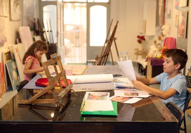 Sanat dersinde yer alan çocuklar, yaratıcı bir atölyede çizim ve resim faaliyetlerine odaklanıyorlar. Genç sanatçılar için parlak ve ilham verici bir ortam..