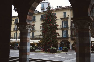 Avrupa şehir meydanının merkezinde güzel dekore edilmiş bir Noel ağacı. Etrafında tarihi binalar ve taş kemer direkleri tarafından yakalanmış şenlikli bir atmosfer var..
