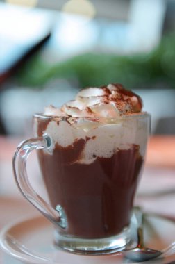 Cam bardakta krem şantili sıcak çikolatanın yakın plan görüntüsü. Sıcak ve rahatlatıcı anlar için mükemmel. Kahve dükkanı promosyonları ve tatlı menüleri için ideal..