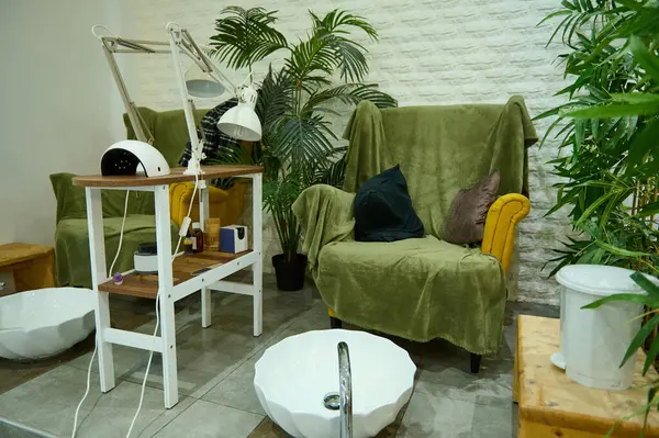 stock image Inviting beauty salon interior with cozy seating for manicures and pedicures, surrounded by lush green plants for a relaxing atmosphere.