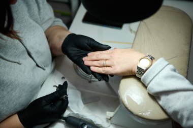 Güzellik salonunda manikür yapan bir tırnak teknisyeninin ellerinin yakın çekimi hassasiyet ve özeni vurguluyor..