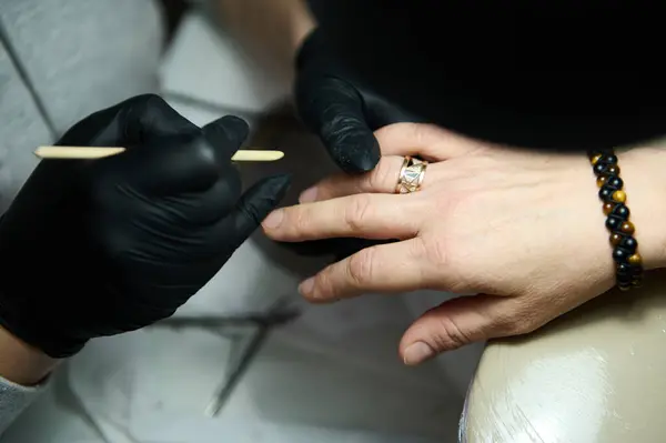 Stock image Close-up of a manicurist wearing black gloves working on a client's nails in a beauty salon. Enhancing nail beauty and care.