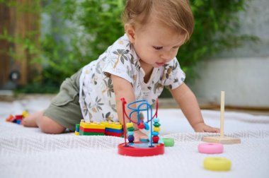 Meraklı bir çocuk açık hava ortamında renkli eğitici oyuncaklarla oynuyor, gelişim etkinliklerine katılıyor..