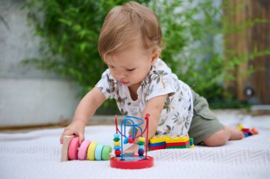 Meraklı bir bebek yumuşak bir paspasın üzerinde canlı oyuncaklarla oynamaya dalmış. Sahne, açık hava ortamında eğlenceli bir keşif ve gelişme anı yakalar..