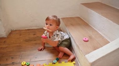 Renkli oyuncaklarla oynarken şort giymiş şirin bir bebek ve yeşil şortla emekliyor. Meraklı bir çocuk evde renkli eğitici oyuncaklarla oynuyor, gelişimsel aktivitelere katılıyor..