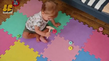 Evde eğitici oyuncaklarla oynayan, renkli bir yapboz halıda sürünen, sevimli erkek bebek manzarası