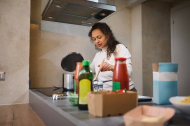 Ev hanımı ev mutfağında yemek pişirirken yemek takımlarını kontrol ediyor..