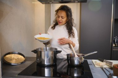 Güzel İtalyan kadın ev mutfağında makarna pişiriyor. Güzel bir ev hanımı, Farfalle makarnasını kaynar suyla dolu bir tavaya doldurup nefis bir aile yemeği yapıyor. İtalyan mutfağı, yemek ve kültürleri.