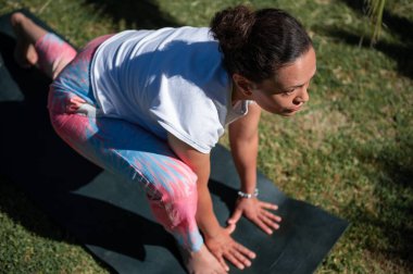 Yoga pozisyonunda bir kadına parkta minder üzerinde odaklanmak, fitness, farkındalık ve sağlıklı yaşam tarzını benimsemek.