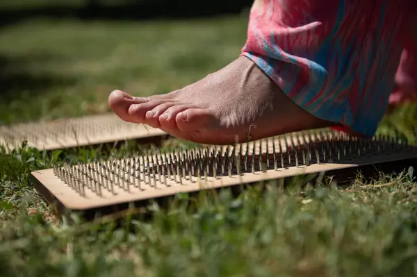 stock image Closeup image of a bare foot stepping on a bed of nails during an outdoor meditation or traditional healing session, focused on alternative therapy and mindfulness.