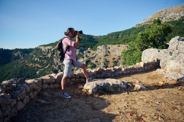 Manzaralı bir dağ manzarasının fotoğraflarını çeken bir adam maceralı bir yürüyüş sırasında doğanın güzelliğini yakalıyor. Seyahat ve yaşam tarzı fotoğrafçılığı için mükemmel bir zaman..