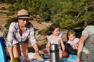 Doğada piknik yapan bir aile. Bir kadın, bir kız ve bir bebek. Kırsalda güneşli bir gün.