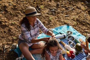 Ormanda piknik yaparken kızının saçını ören bir anne. Doğada ailece güzel vakit geçiriyorlar..