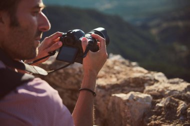 Odaklanmış bir fotoğrafçı, dijital bir kamera kullanarak güzel bir dağ manzarasının fotoğraflarını çekiyor. Sahne macera, doğa ve yaratıcılığı resmediyor..