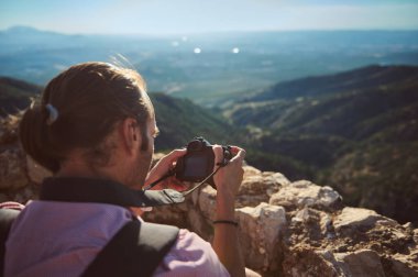 Adam dijital kamerayla nefes kesici bir dağ manzarasının fotoğraflarını çekiyor. Sakin ve ilham verici doğa macerası..