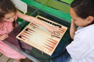 Genç bir anne ve kızı cam bir masada tavla oynarken birbirlerine bağlanıyorlar. Anne, kızı hamlesini yaparken onu izler ve bir aile birlikteliği katar..