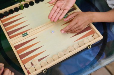 Tahta bir masa oyununda tavla oynayan iki kişinin üst görüntüsü. Stratejik bir oyuna girişmek, açık havada eğlenmek ve kaliteli zaman geçirmek..