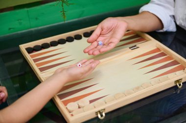 Tahta bir tahtanın üzerinde tavla oynarken iki elin zarı sallaması. Boş zaman temaları, aile zamanları ve geleneksel masa oyunları için mükemmel..