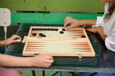 İki insan tahta bir tahtanın üzerinde tavla oynuyor, oyundan zevk alıyor ve birlikte kaliteli zaman geçiriyorlar..