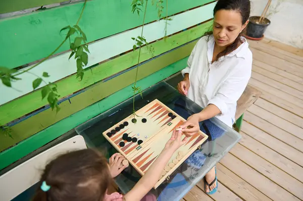 Anne ve kızı güneşli bir ahşap güvertede birlikte tavla oynamaktan hoşlanırlar. Aile bağları ve boş zaman..