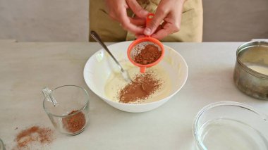 Kakao tozunu bir kase hamura karıştıran kişi ev yapımı İtalyan tatlısı için malzemeleri karıştırıyor. Sıcak bir mutfak ortamında pişirme sürecini yakalıyorum..