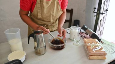 İtalyan tiramisusu yapan kişi kahve, mascarpone peyniri ve kadın parmağı gibi malzemeler kullanıyor. Ev mutfağında klasik bir tatlı hazırlıyorum..