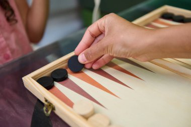 Tavla oynayan ellerin yakın plan görüntüsü oyun tahtası ve parçalarının detaylarını gösteriyor. Aile bağları ve boş zaman aktivite kavramları için mükemmel..