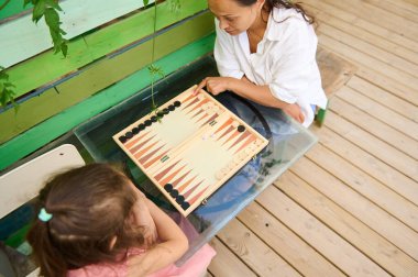 Bir anne ve kızı ahşap bir güvertede arkadaşça bir tavla oyunu oynuyorlar. Sahne, bağ kurma ve gevşeme anlarını yakalar..