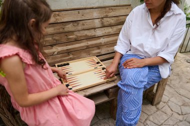 Anne ve kızı dışarıda tavla oynayarak güzel vakit geçiriyorlar. Görüntü bir bağ anı yakalar ve aile eğlence aktivitelerinin neşesini..