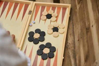 Ahşap bir masada oynanan tavla oyununun yakın plan çekiminde zar ve dama oynanır..