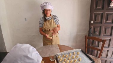 Female baker in chef hat and apron instructing someone on how to make croissants in a cozy kitchen area with a rustic door. clipart