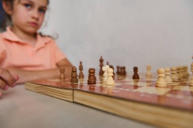 Satranç oynarken çok odaklanmış genç bir kız. Konsantrasyon ve strateji ortada. Satranç taşları tahtada belirgin bir şekilde görünür..