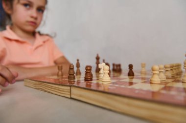 Satranç oynarken çok odaklanmış genç bir kız. Konsantrasyon ve strateji ortada. Satranç taşları tahtada belirgin bir şekilde görünür..