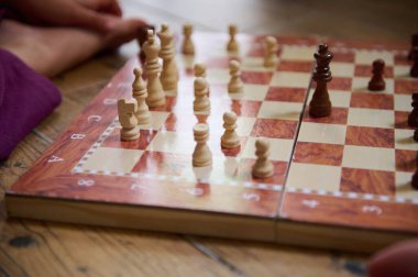 Oyunun yakın plan satrancı, oyun oyunundaki odak ve stratejiyi vurgulayarak, tahta bir tahtada stratejik parça düzenini gösteriyor.