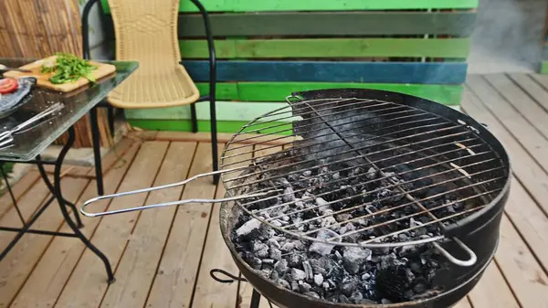 Açık hava barbekü sahnesi, ahşap bir verandada temiz bir ızgara, yakınlarda taze sebzeler, yaz pikniği ya da toplanma için mükemmel..