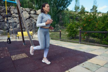 Kadın parkta egzersiz yapıyor, yeşil ortamda sağlıklı yaşam tarzını ve uygunluğunu sergiliyor..