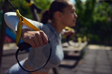 Açık havada uzaklaştırma eğitimi alan bir kadın güneşli bir park ortamında dayanıklılık ve zindeliğe odaklanıyor..