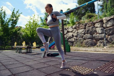 Parkta kardiyo yapan bir kadın. Spor giyim kuşamında güneşli bir günde spor salonunda spor yaparken spor, sağlık, açık hava aktivitesi ve kararlılık yakalar..