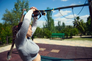 Park 'taki direniş bandını spor programını geliştirmek için kullanan bir kadın. Parlak güneşli bir gün kararlılığını arttırır ve odaklanır..