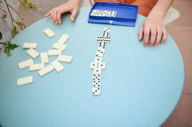 Eller mavi bir masada domino oynuyor. Dağınık fayanslar çekici ve eğlenceli bir atmosfer olduğunu gösteriyor..