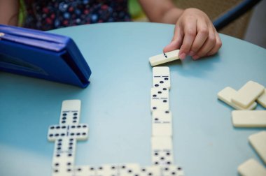 Çocuk domino oynamaya odaklanmış, bir sonraki hamleyi planlıyordu. Çekici ve stratejik, aile eğlencesi için mükemmel..