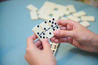 Domino oynayan ellerin yakın plan çekimi, rahat bir ortamda strateji ve karar verme üzerine odaklanmak.