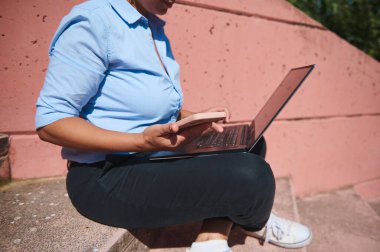 İş kadını bilgisayarlı ve akıllı telefonlu birden fazla görev dış basamaklarda, modern uzaktan çalışmayı ve bağlantıyı simgeliyor.